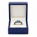 14k black gold engagement ring with three blue diamonds totaling 1.0 ct, displayed in a royal blue wooden box.