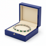 14k gold emerald and diamond tennis bracelet with baguette cuts, showcasing sparkling gemstones in a jewelry box.