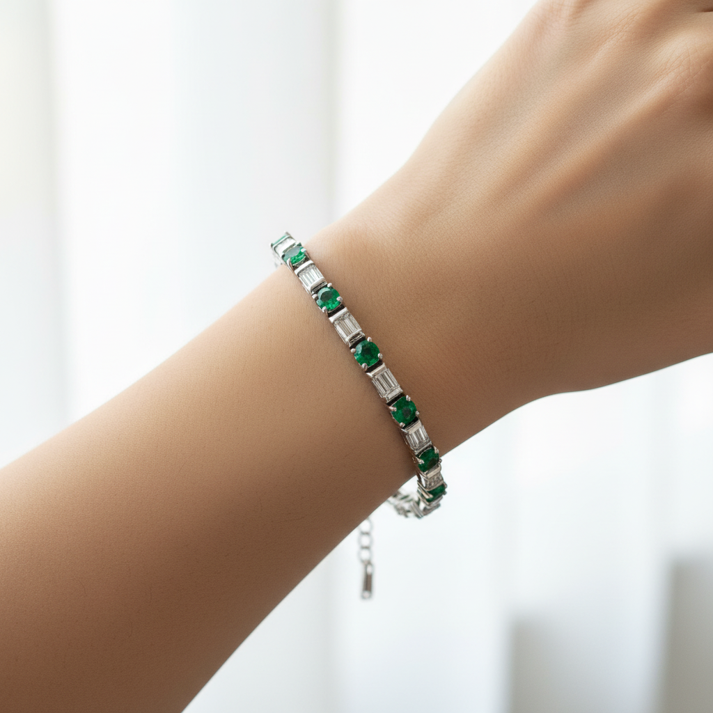 14k gold emerald and diamond tennis bracelet with baguette-cut stones, featuring 5.50 carats total weight, worn on a model.