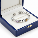 14k white gold multi-colored gemstone bracelet with oval-cut stones, displayed in a royal blue wooden box.