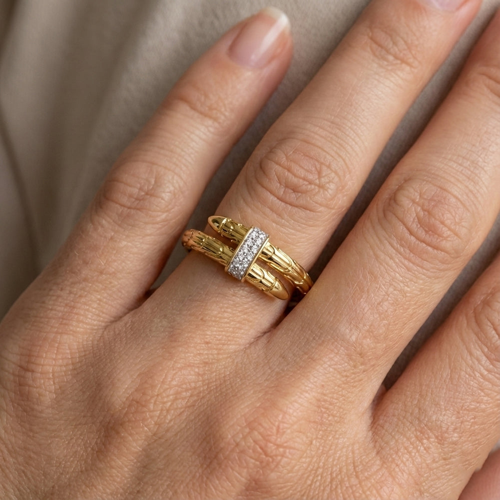 Gold ring with a diamond on a person's finger against a neutral background