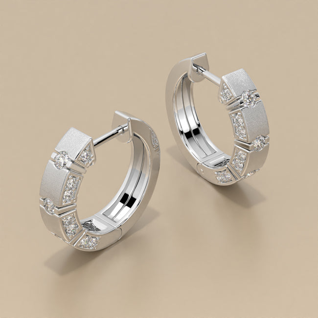 Pair of gold hoop earrings with embedded diamonds on a beige background