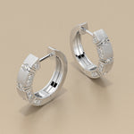 Pair of gold hoop earrings with embedded diamonds on a beige background