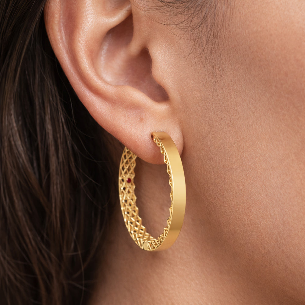 Gold hoop earrings worn by a person with dark hair.