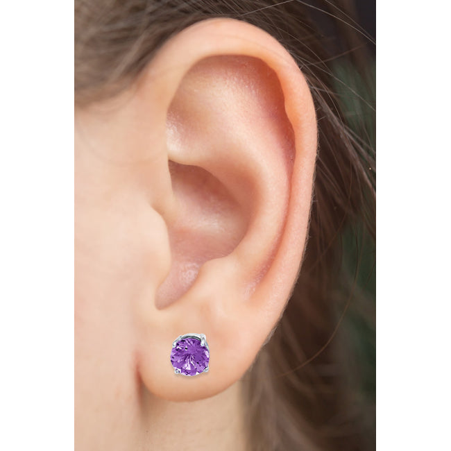 Close-up of an ear wearing a purple stud earring with blurred background