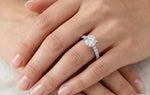 Close-up of a hand wearing a diamond ring on a neutral background