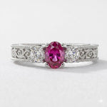 14K white gold oval ruby diamond fashion ring with 1.50 carats total weight, featuring a stunning central ruby and sparkling diamonds.