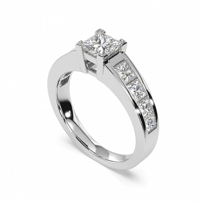 A princess-cut diamond engagement ring in a polished white-colored metal band with a channel-set row of diamonds on the shank, shown on a clean white background.