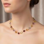 A  gold necklace with multicolored gemstones on a woman's hand