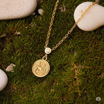 Gold necklace with a pendant on a green moss background