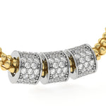 A close-up of a gold and silver pavé necklace featuring three cylindrical spacers covered in clear stones, set against a plain white background.