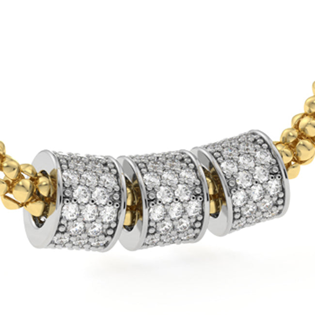 A close-up of a gold and silver pavé necklace featuring three cylindrical spacers covered in clear stones, set against a plain white background.