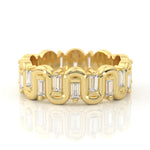 A yellow gold eternity-style ring featuring baguette and round-cut clear stones, shown on a clean white background with a soft reflection below.