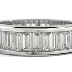 A close-up of a white-toned ring featuring a row of clear baguette-cut gemstones set in a polished band, shown against a white background.