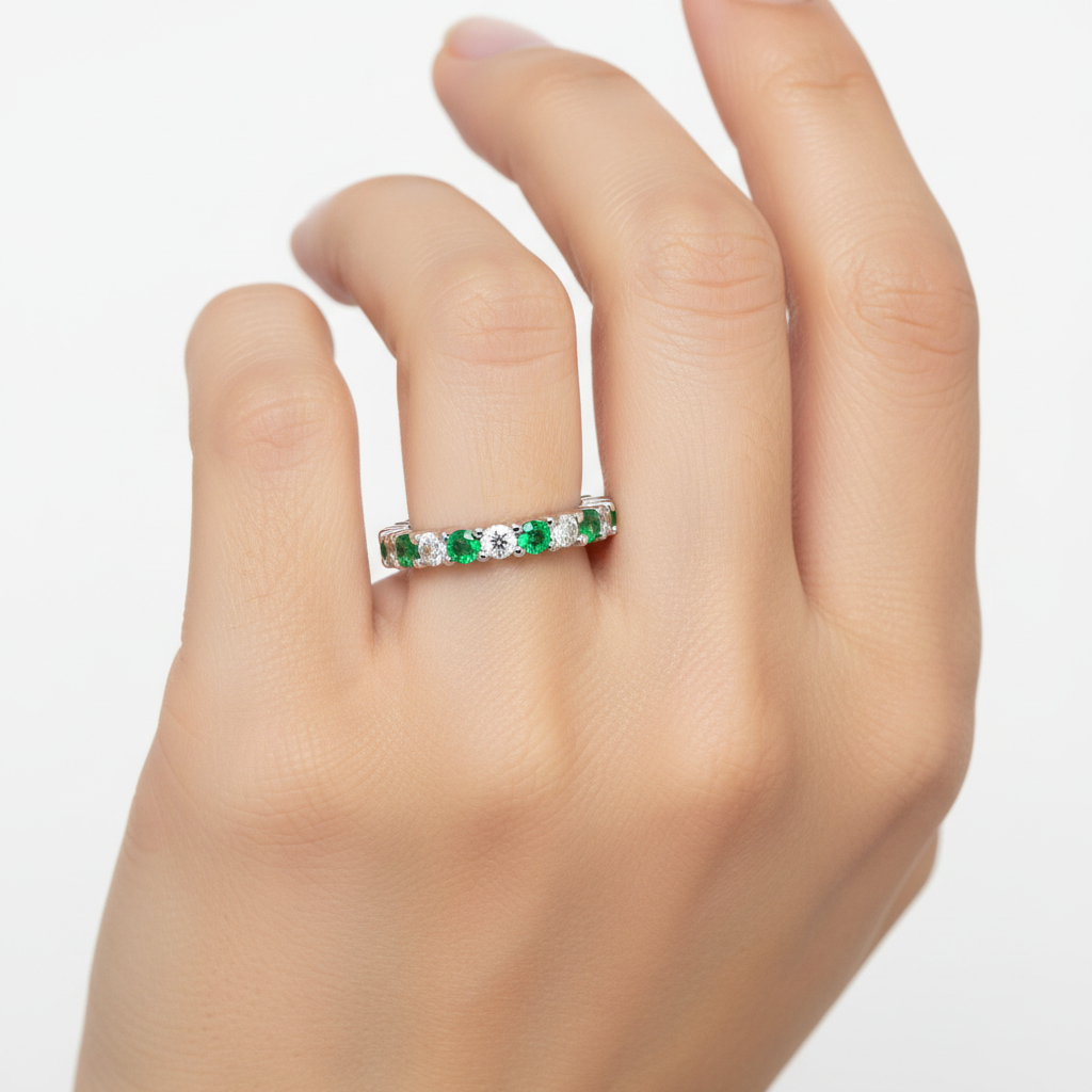 14k gold diamond and green emerald eternity wedding band on a model, featuring sparkling stones and intricate design.