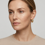 Full-face model wearing yellow-gold caviar huggie earrings